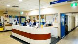 Long shot of a a medical reception desk where several Mercy Health workers are working.