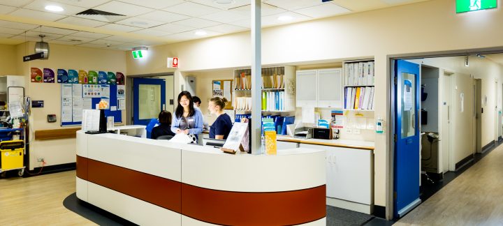 Long shot of a a medical reception desk where several Mercy Health workers are working.