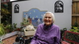 Florence Gibbs at home in the garden with one of her mosaic masterpieces