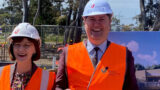 Two people wearing high vis jackets and hardhats over business wear